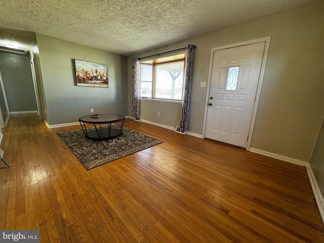 foyer entrance with a textured ceiling, baseboards, and hardwood / wood-style flooring