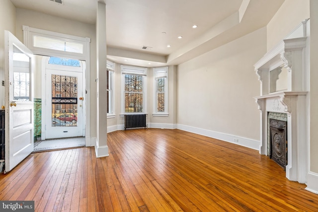 foyer with visible vents, radiator, a fireplace, and hardwood / wood-style flooring