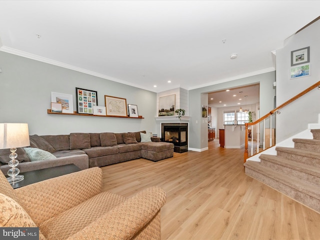 living area featuring a multi sided fireplace, baseboards, stairs, light wood-type flooring, and crown molding