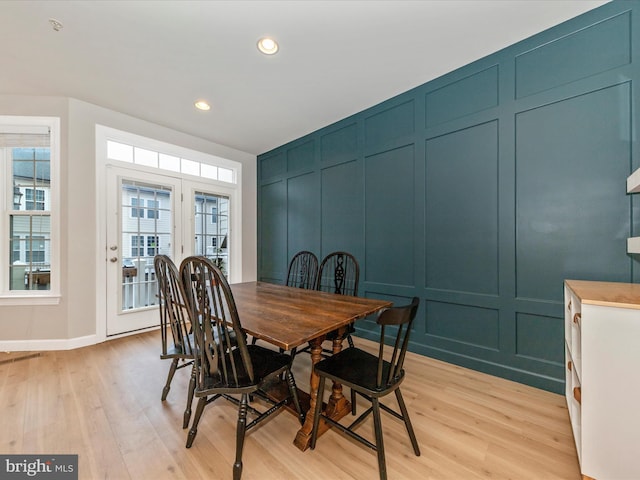 dining room featuring recessed lighting, a decorative wall, and light wood finished floors