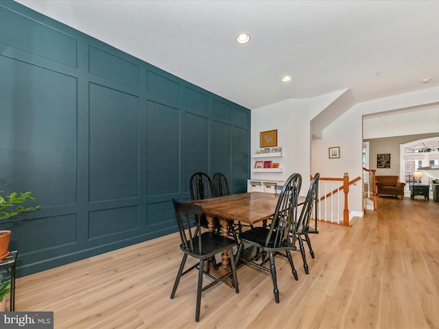 dining space featuring recessed lighting, a decorative wall, and light wood finished floors