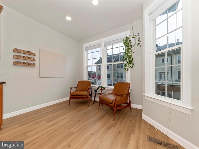 sitting room featuring a healthy amount of sunlight, visible vents, light wood-style flooring, and baseboards