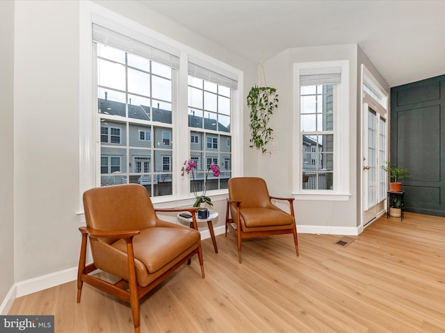 living area featuring light wood finished floors, baseboards, and visible vents