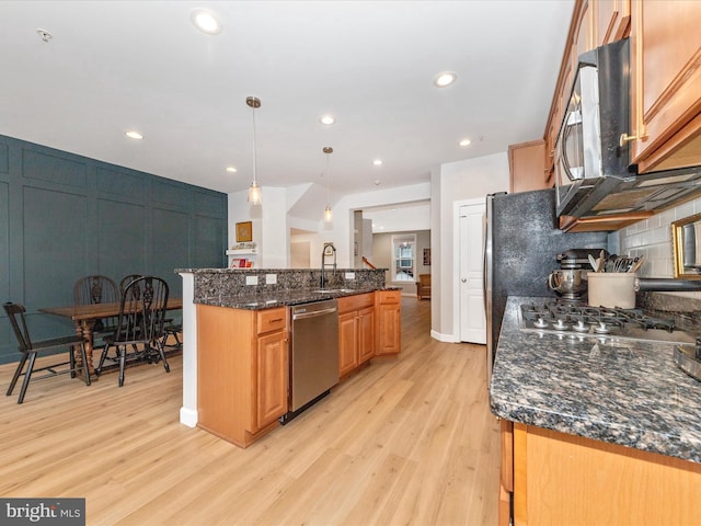 kitchen with a sink, light wood-style flooring, stainless steel appliances, and backsplash