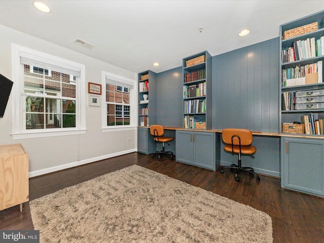 office space featuring visible vents, built in desk, and wood finished floors