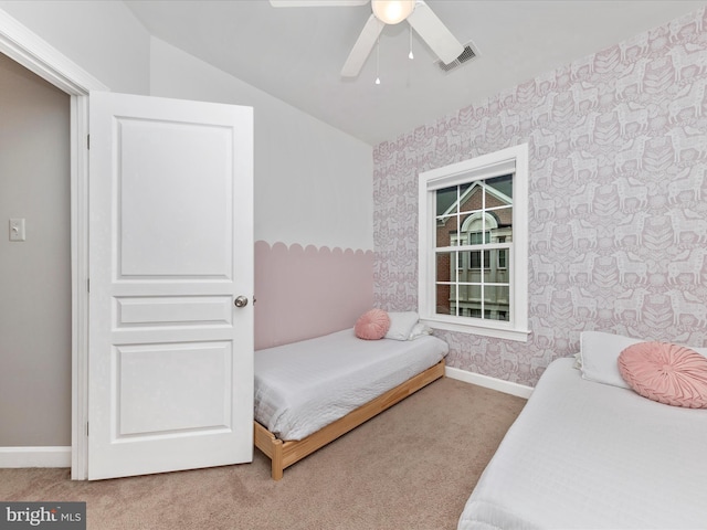 carpeted bedroom with visible vents, vaulted ceiling, baseboards, and wallpapered walls