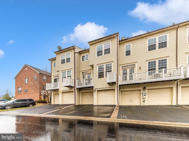 view of front facade with a residential view, aphalt driveway, and community garages