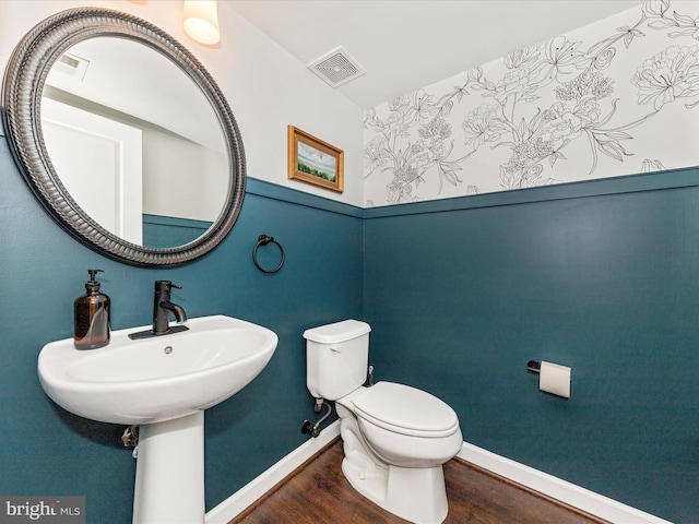 bathroom featuring toilet, wood finished floors, visible vents, and baseboards