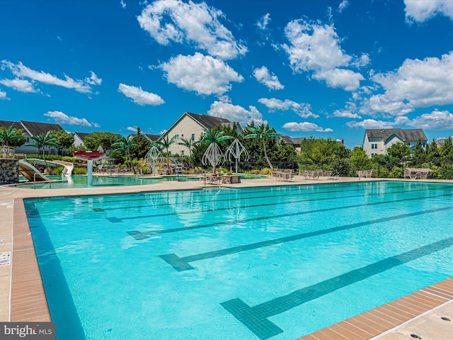 community pool with a patio area and fence