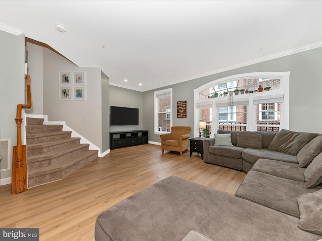 living room with ornamental molding, light wood finished floors, stairway, and visible vents