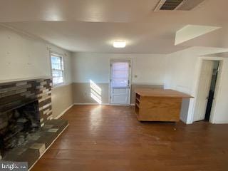 unfurnished living room featuring visible vents, a fireplace with raised hearth, and wood finished floors