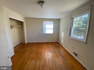 unfurnished bedroom with a closet, wood finished floors, and baseboards