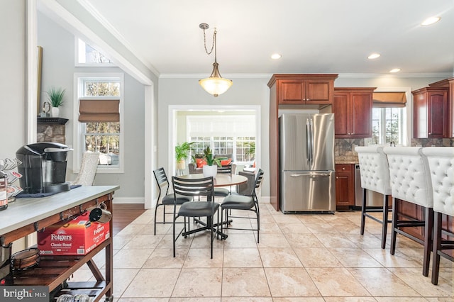 kitchen with a wealth of natural light, backsplash, ornamental molding, and freestanding refrigerator