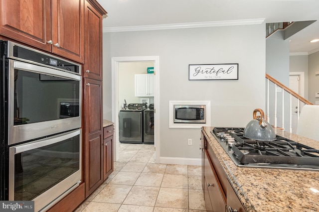 kitchen with crown molding, baseboards, washing machine and dryer, appliances with stainless steel finishes, and light tile patterned flooring