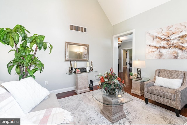 living room with high vaulted ceiling, wood finished floors, visible vents, and baseboards