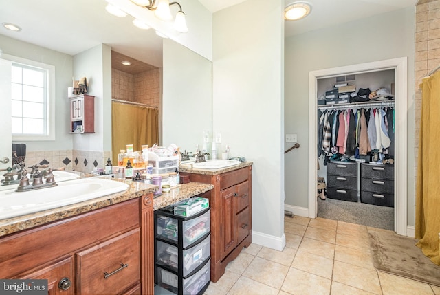 bathroom featuring a walk in closet, baseboards, a shower with shower curtain, tile patterned floors, and vanity