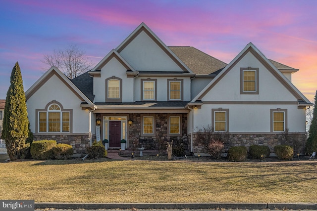 view of front of home featuring stone siding, stucco siding, and a front yard