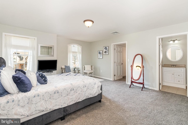 bedroom with ensuite bathroom, visible vents, baseboards, and carpet floors