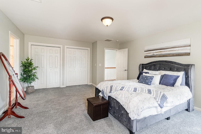 bedroom featuring baseboards, carpet flooring, two closets, and visible vents