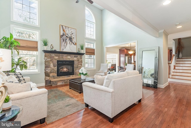 living area with plenty of natural light, a fireplace, stairs, and hardwood / wood-style floors