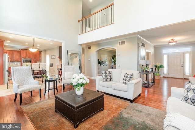 living room featuring visible vents, light wood-style floors, and crown molding