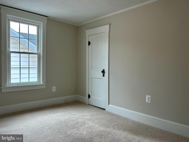 carpeted spare room with ornamental molding and baseboards