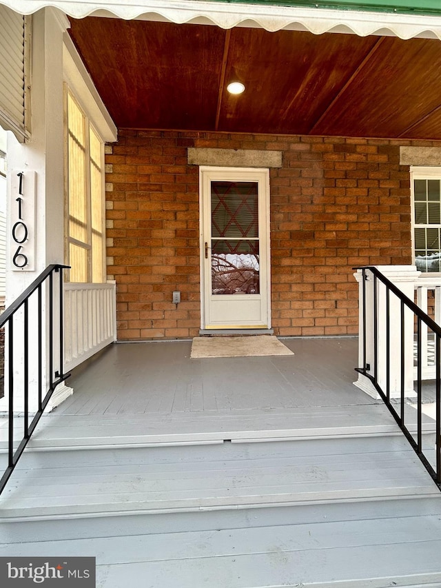 view of exterior entry with covered porch and brick siding