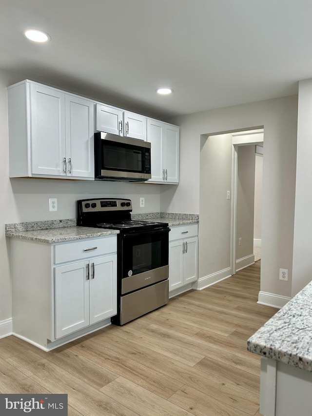 kitchen with light wood-style floors, baseboards, white cabinetry, and stainless steel appliances