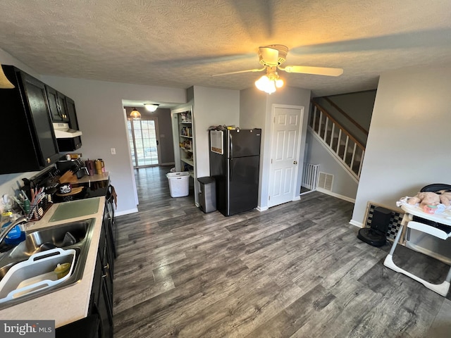 kitchen featuring visible vents, a sink, freestanding refrigerator, and dark wood-style floors