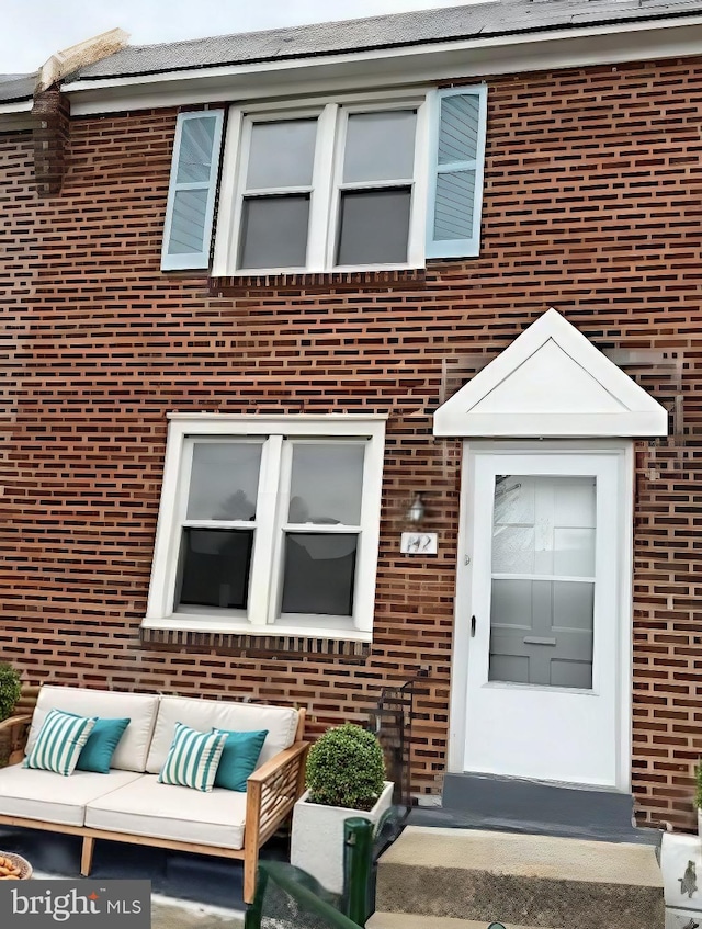 doorway to property featuring outdoor lounge area and brick siding