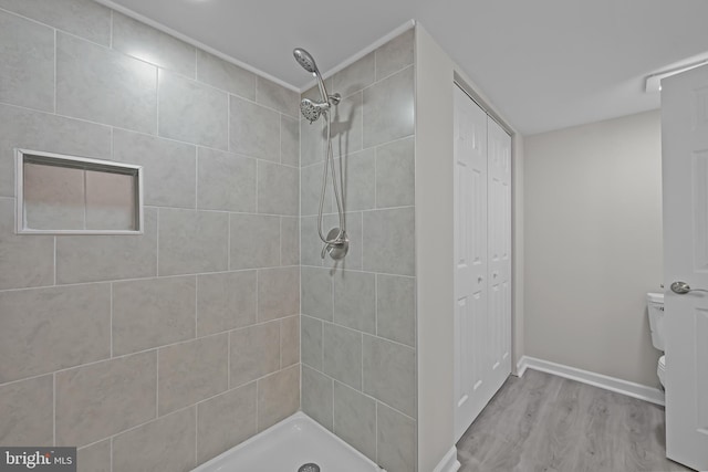 full bath featuring wood finished floors, a closet, a shower stall, and toilet