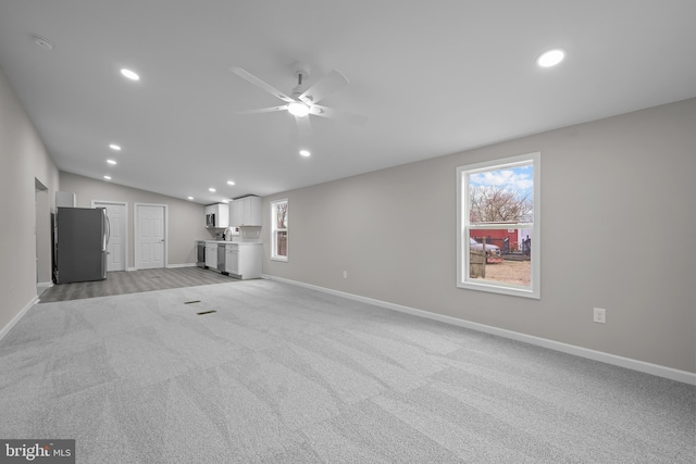 unfurnished living room with plenty of natural light, light carpet, vaulted ceiling, and recessed lighting