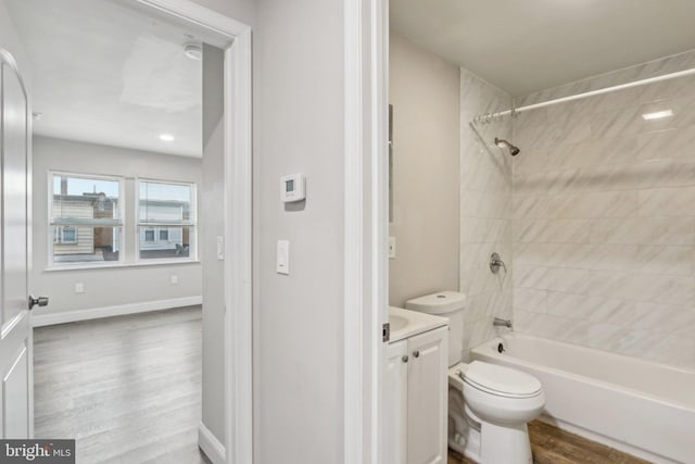 bathroom featuring baseboards, toilet, shower / bathing tub combination, wood finished floors, and vanity