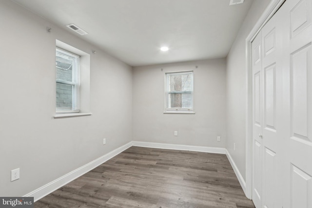 unfurnished bedroom with a closet, visible vents, baseboards, and wood finished floors