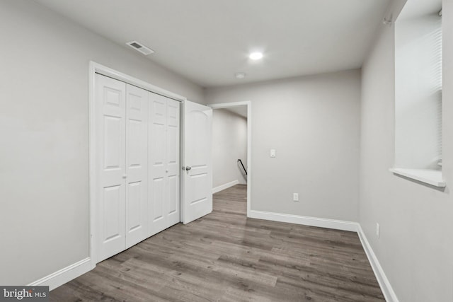 unfurnished bedroom featuring a closet, baseboards, visible vents, and wood finished floors