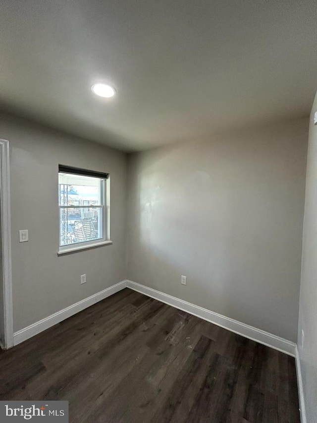 spare room with dark wood-style floors and baseboards