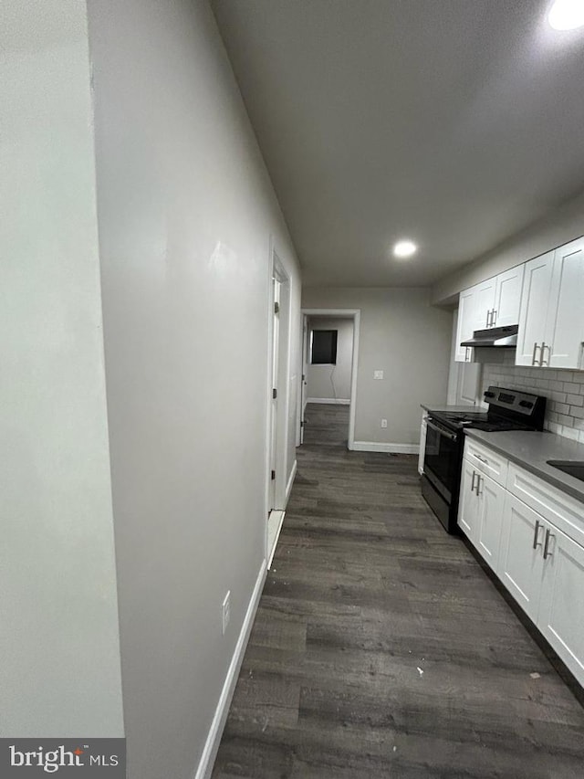 kitchen featuring backsplash, under cabinet range hood, range with electric stovetop, white cabinetry, and dark wood-style flooring