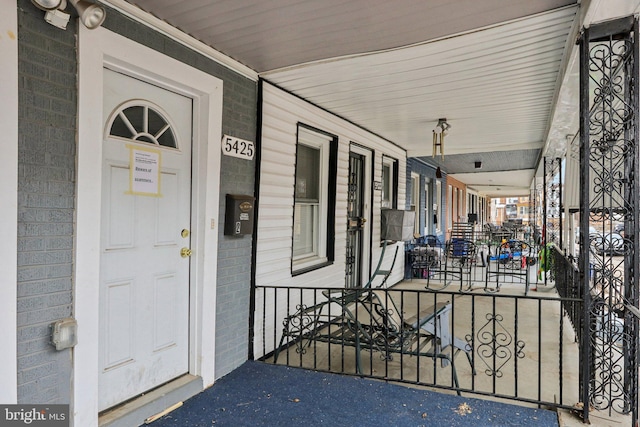 view of exterior entry featuring brick siding and a porch