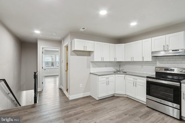 kitchen featuring under cabinet range hood, light wood-type flooring, stainless steel range with electric stovetop, white cabinets, and a sink