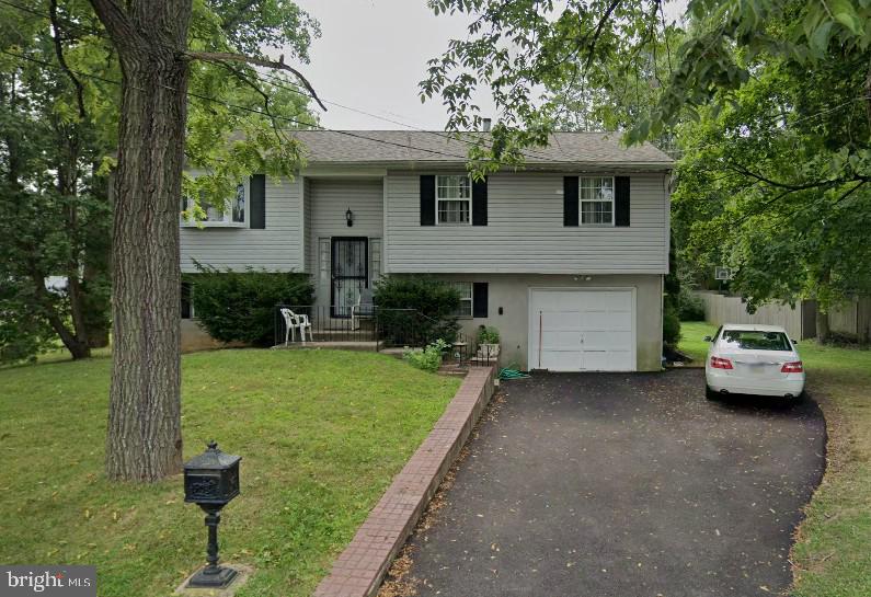 split foyer home with aphalt driveway, a front yard, and an attached garage