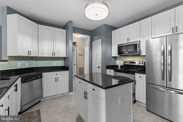 kitchen featuring stainless steel appliances, white cabinetry, decorative backsplash, a center island, and dark stone counters