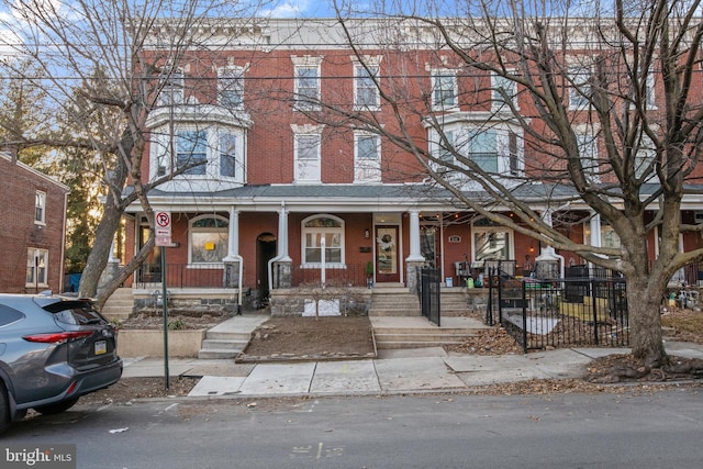 view of property featuring a porch, fence, and brick siding