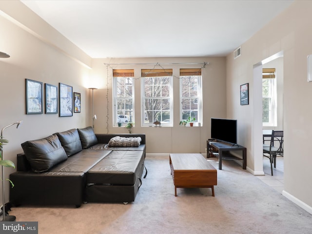 living room featuring a wealth of natural light, visible vents, baseboards, and carpet floors