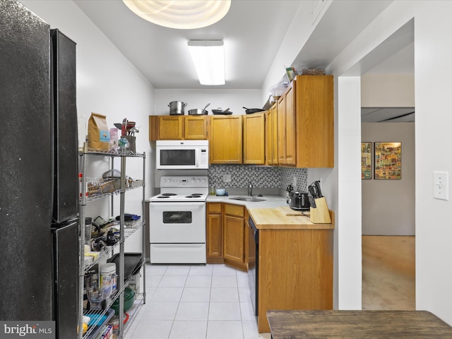 kitchen with brown cabinets, black appliances, a sink, tasteful backsplash, and light tile patterned flooring