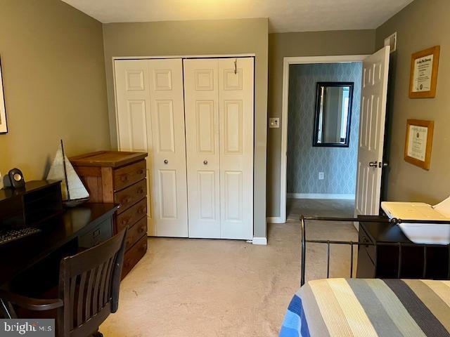 bedroom with light carpet, baseboards, and a closet