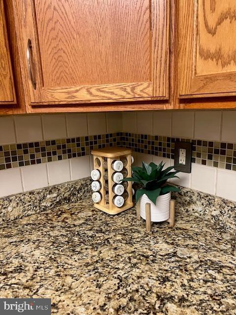 room details with tasteful backsplash, stone counters, and brown cabinets