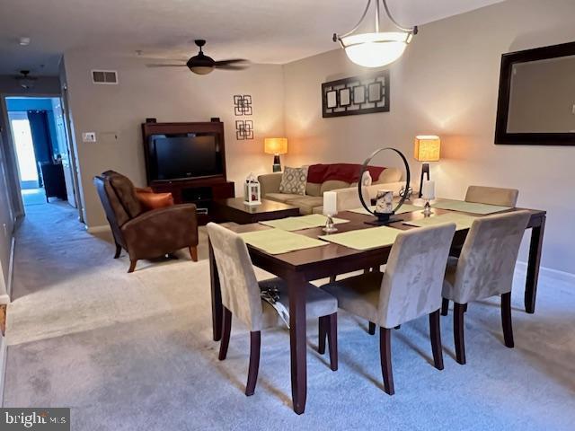 dining area featuring baseboards, light colored carpet, visible vents, and ceiling fan