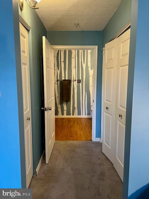 hallway with baseboards, carpet floors, and a textured ceiling