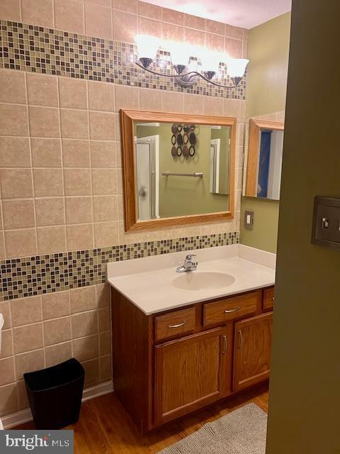 bathroom with backsplash, tile walls, wood finished floors, and vanity