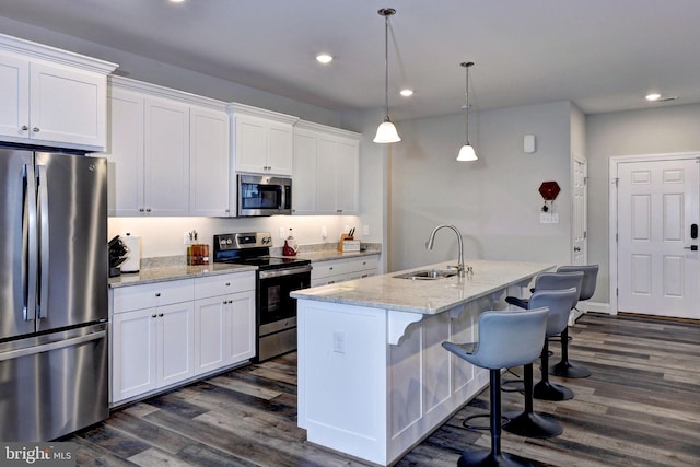 kitchen with dark wood finished floors, white cabinets, appliances with stainless steel finishes, and a sink